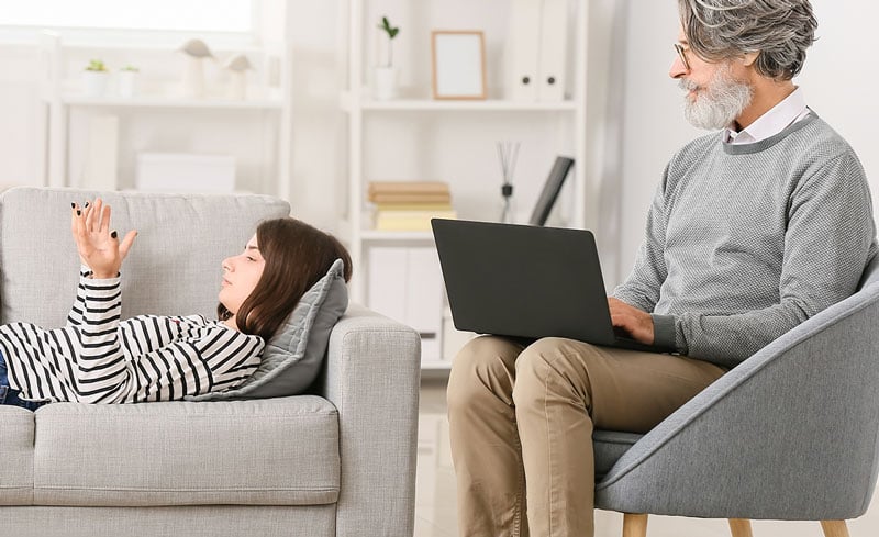 therapist on laptop and teen in therapy