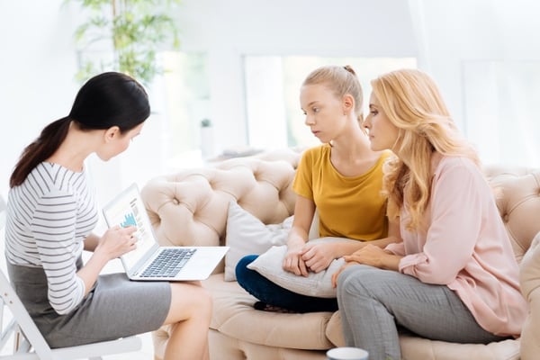 therapist showing results to mother and daughter looking at the laptop screen